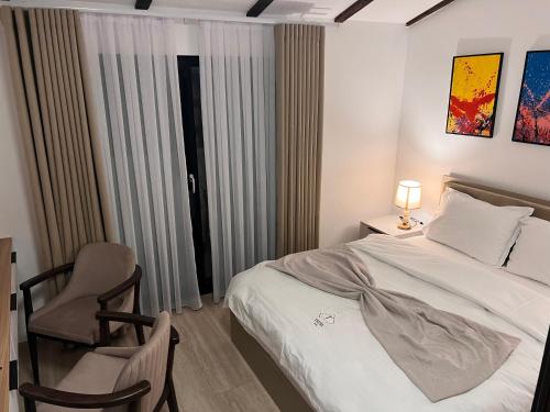 a bedroom with a bed and a chair and a window at Treva Hotel & Apartaments in Prizren