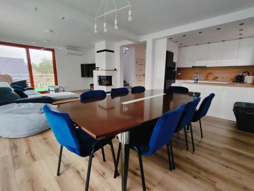 a kitchen and dining room with a table and blue chairs at Oaza U Leszka-dom całoroczny z sauną i ruską banią in Podgórze