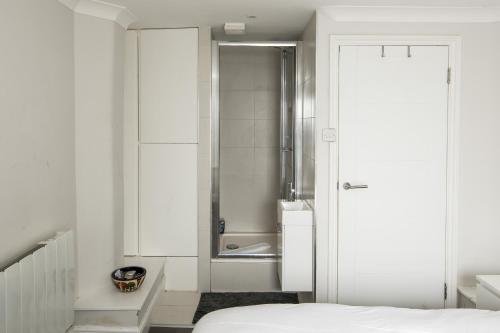 a white bedroom with a shower and a bed at Ideal 1BD Flat Shoreditch For City Explorers in London