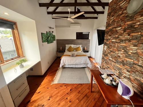 ein Schlafzimmer mit einem Bett und einer Ziegelwand in der Unterkunft The Wood House in Empangeni