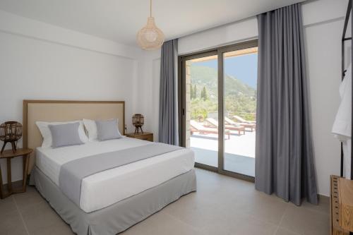 a bedroom with a white bed and a large window at Christdilia villas in Palaiokatoúna