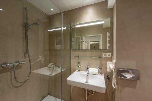 a bathroom with a shower and a sink and a mirror at PANORAMA HOTEL in Neustadt an der Weinstraße in Neustadt an der Weinstraße