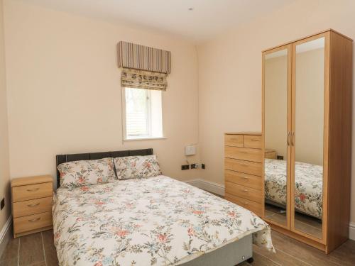 een slaapkamer met een bed, een dressoir en een spiegel bij Skipper in Lancaster