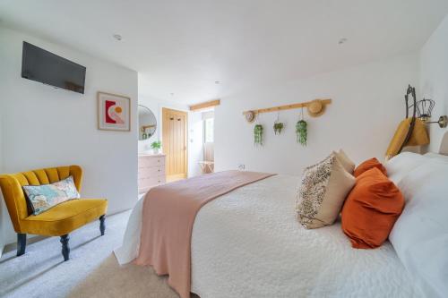 um quarto branco com uma cama e uma cadeira em The Granary em Camelford