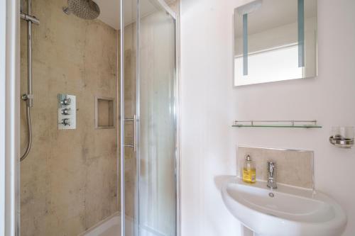 uma casa de banho branca com um lavatório e um chuveiro em The Granary em Camelford