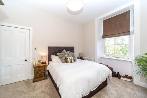 1 dormitorio con cama blanca y ventana en Montgomery Large 2 Bedroom Flat - 5 Mins Walk to City Centre en Edimburgo