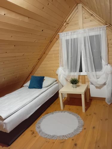 a bedroom with a bed and a table in a attic at Wróblówka- domek na wsi in Parczew