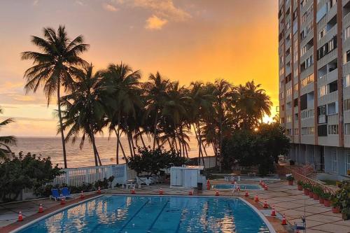 a hotel swimming pool with a sunset in the background at Ocean View 1 Bedroom Cabana in Condado! in San Juan