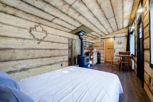 a large bed in a room with a wood wall at Your Cozy Cabin Retreat in Saint-Rémi-dʼAmherst