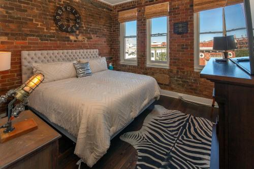 a bedroom with a bed and a brick wall at Charming Savannah Penthouse: Grand Views & Dual Parking in Savannah