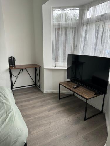 a living room with a flat screen tv and a table at High street home in Eastleigh