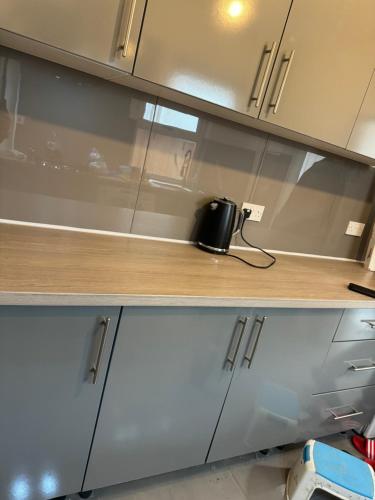 a kitchen with white cabinets and a wooden counter top at High street home in Eastleigh