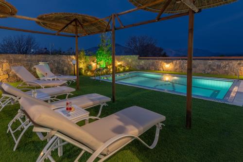 a pool with chaise lounge chairs and an umbrella at Treasure of Herbs Complex in Panormos Rethymno
