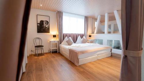 a bedroom with a bed and a large window at Hotel & Restaurant Rössli in Stansstad