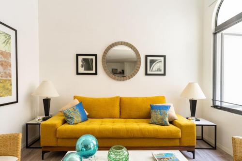 a yellow couch in a living room with a mirror at Increíble Loft en Centro Histórico de Guadalajara in Guadalajara