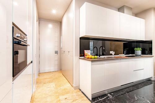 a kitchen with white cabinets and fruits on the counter at Premium Belgravia Harrods Apartment in London