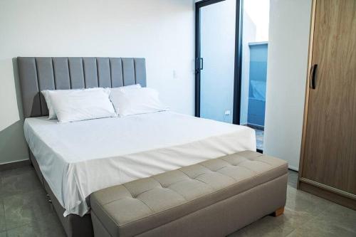 a bedroom with a large white bed with a bench at Apartamento frente al CC Viva Envigado in Envigado