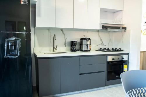 a kitchen with white cabinets and a sink and a stove at Apartamento frente al CC Viva Envigado in Envigado