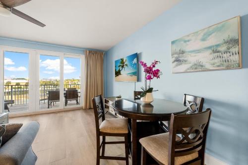 a dining room with a table and chairs and a balcony at Lovely Resort Low Floor Condo! Just Steps to the Beach & Restaurants! by Dolce Vita Getaways PCB in Panama City Beach