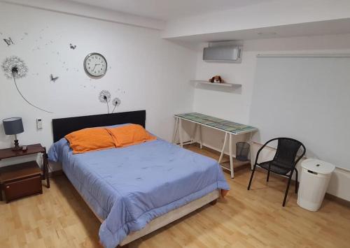 1 dormitorio con cama, escritorio y reloj en Casa campestre con las comodidades de la ciudad, en Jamundí