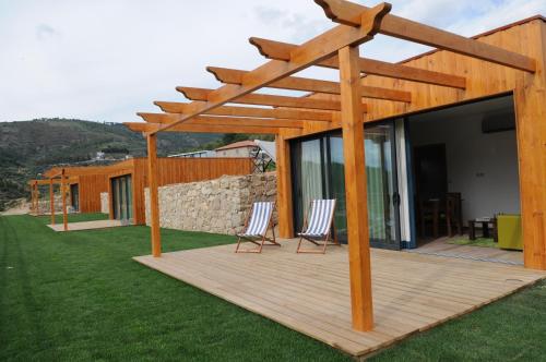 a wooden deck with two chairs under a wooden pergola at Douro Cister Hotel Resort in Ucanha