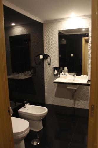 a bathroom with a white toilet and a sink at Douro Cister Hotel Resort in Ucanha