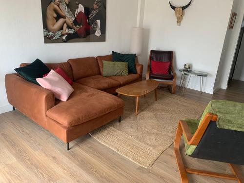 a living room with a brown couch and two chairs at Midway Apartamento in Torremolinos