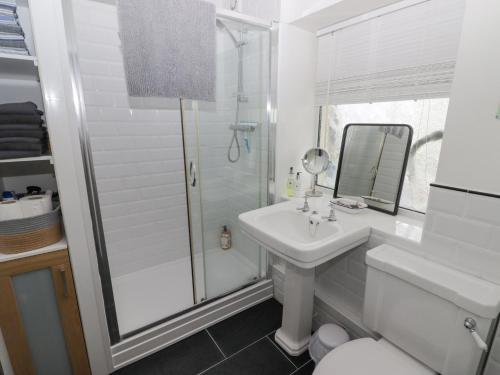 a white bathroom with a sink and a shower at Harbour Village Views in Goodwick
