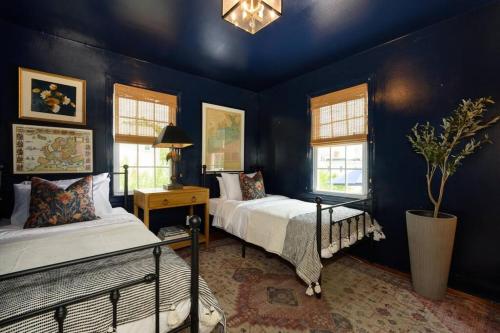 two beds in a room with blue walls and windows at Charming Beachside Home in Bridgeport