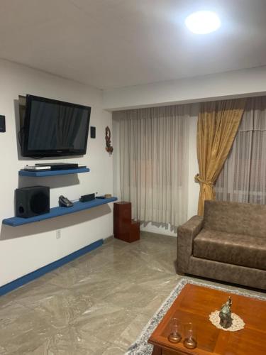 een woonkamer met een bank en een flatscreen-tv bij CONFORTABLE APARTAMENTO in Bogota