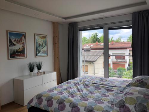 - une chambre avec un lit et une grande fenêtre dans l'établissement 2 Ljubljana Modern Villa Apartment, à Ljubljana