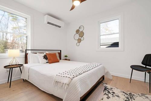 1 dormitorio blanco con 1 cama y 2 ventanas en New Paltz Zen Wellness Cabin w/ Hot Tub, en New Paltz