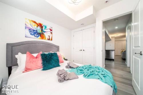 a bedroom with a white bed with pink and blue pillows at *Vibrant Suite* Long Stays - Wi-Fi - Fireplace - NFLX in Edmonton