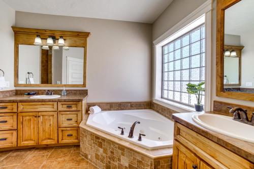 a bathroom with a tub and a sink and a mirror at Welcoming Rigby Home with Game Room and Fire Pit! in Rigby