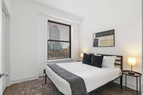 a white bedroom with a large bed and a window at 1BR Modern Apartment in Chicago - Del Prado 811 in Chicago