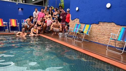 eine Gruppe von Menschen, die um einen Pool herum sitzen in der Unterkunft Ô de Casa Hostel in São Paulo