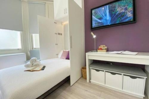 ein Schlafzimmer mit einem Bett und einem TV an der Wand in der Unterkunft Apt 04 Seaside Serenity Chic Studio Steps to Promenade in Brighton & Hove