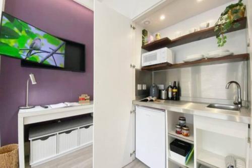 cocina con armarios blancos y TV en la pared en Apt 04 Seaside Serenity Chic Studio Steps to Promenade en Brighton & Hove