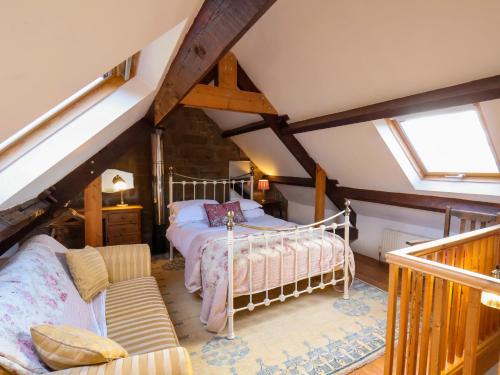 um quarto com uma cama e um sofá no sótão em Daffodil Cottage em Danby