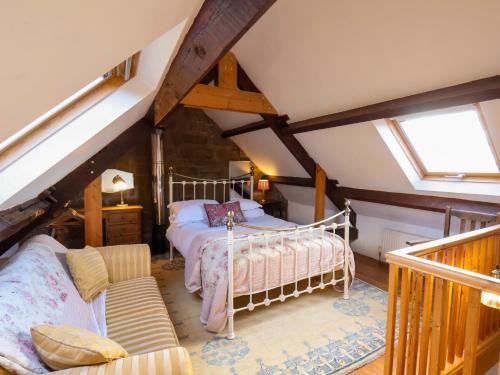 una camera da letto con un letto e un divano in mansarda di Daffodil Cottage a Danby