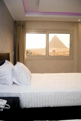 a hotel room with a bed with a window with the pyramid at Egypt Pyramids Inn in Cairo