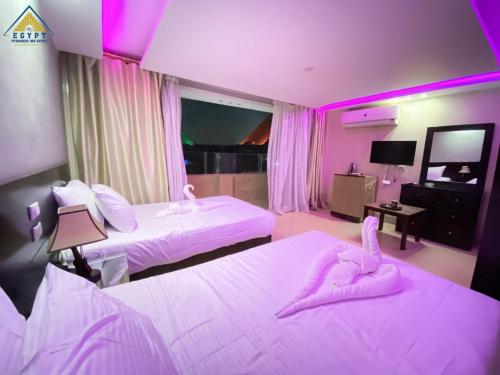 a hotel room with two beds with pink lighting at Egypt Pyramids Inn in Cairo