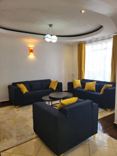 una sala de estar con sofás azules y una mesa. en Diana executive residents, en Kisumu