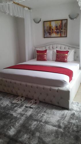 1 dormitorio con 1 cama grande con almohadas rojas en Diana executive residents, en Kisumu