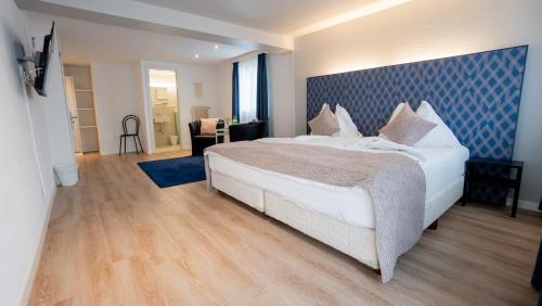 a bedroom with a large bed with a blue headboard at Hotel & Restaurant Rössli in Stansstad