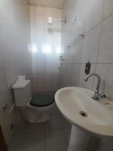 a white bathroom with a toilet and a sink at Quarto para temporada in Ribeirão Preto