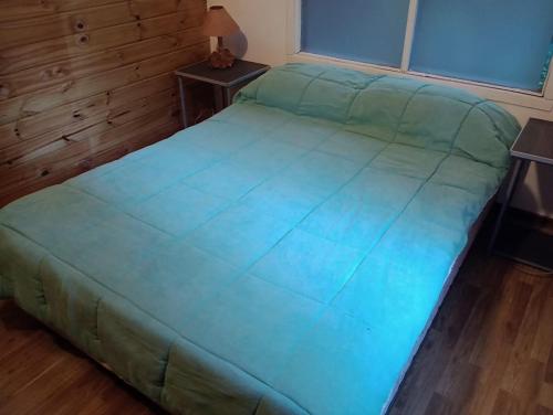 a bed in a room with a green bedspread at CABAÑA CASA DE PIEDRA in San Carlos de Bariloche