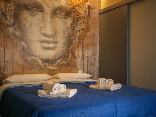 Una cama con toallas encima con una pintura en Dea's Rooms, en Noto