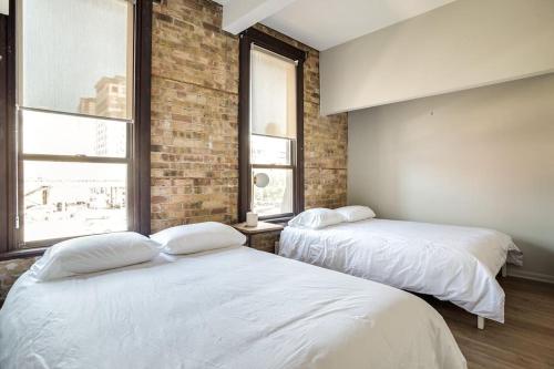 two white beds in a room with two windows at The Orleans - Floor 2 Private roof deck Patio in Chicago