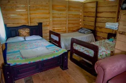 a bedroom with two beds and a chair at Pozas Guacimo in Guápiles